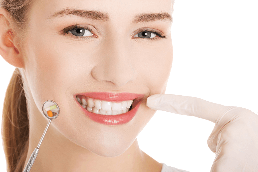 Eine lächelnde Frau mit makellosen Zähnen zeigt auf ihren Mund, während sie einen Zahnarztspiegel hält, der einen ihrer Zähne reflektiert. Sie hat ein freundliches Gesicht, klare Haut und trägt kein sichtbares Make-up. Der Hintergrund des Bildes ist weiß und transparent.
